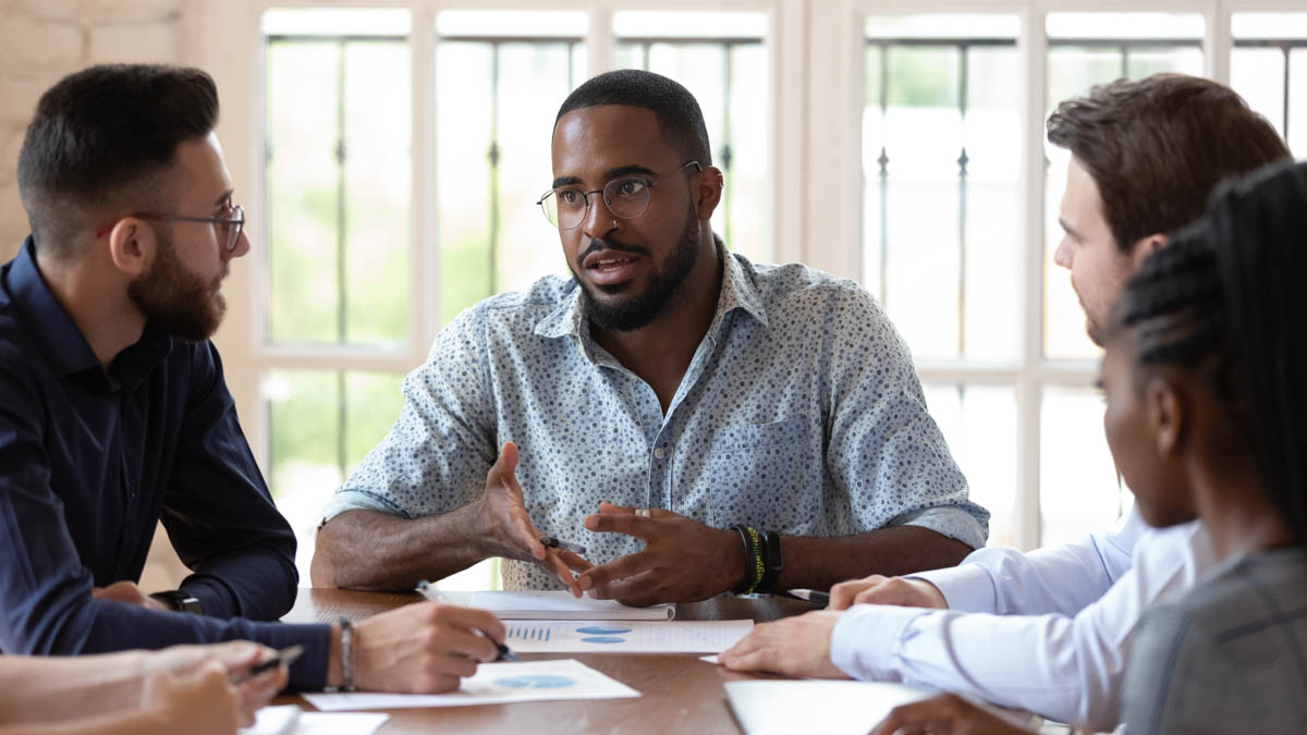 Concentrated African Amrican Male Manager Talking To Diverse Colleagues.