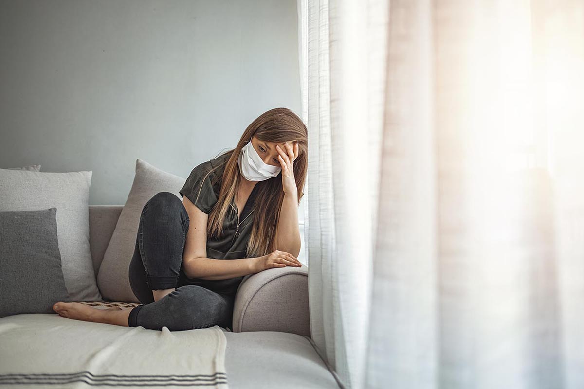 Sad Lonely Girl Isolated Stay At Home In Protective Sterile Medical Mask On Face Looking At Window