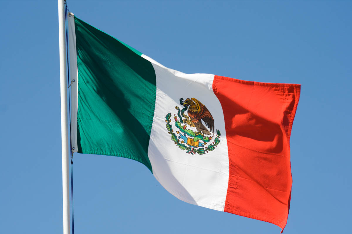 mexican flag, national banner of mexico waving against blue sky