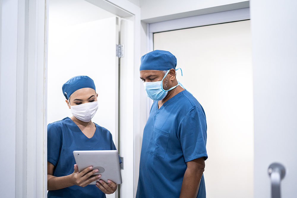 healthcare coworkers walking and analyzing digital tablet at hospital wearing face mask