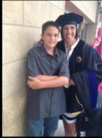 Matthew Towle and Kelly Jennings-Towle pictured together in a pose after Kelly’s doctoral graduation. She is seen here in her regalia.