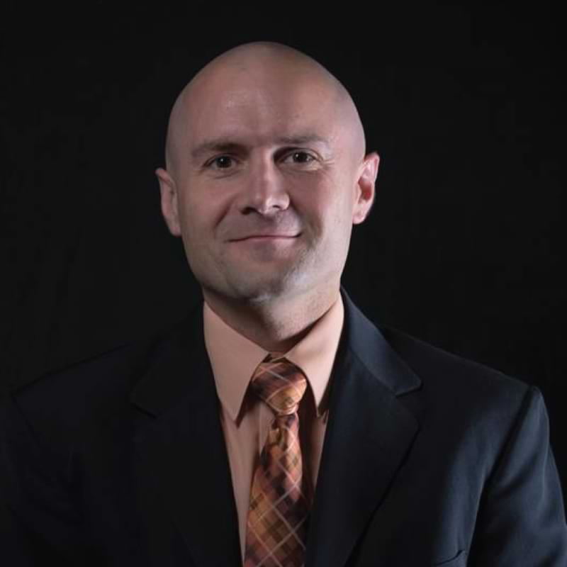 Headshot on black background of University of Central Florida Faculty Senate Chair for 2026-2027, Dr. Jeff Kauffman, College of Engineering and Computer Science. In the picture he’s wearing a dark jacket, orange shirt and multi-colored tie.