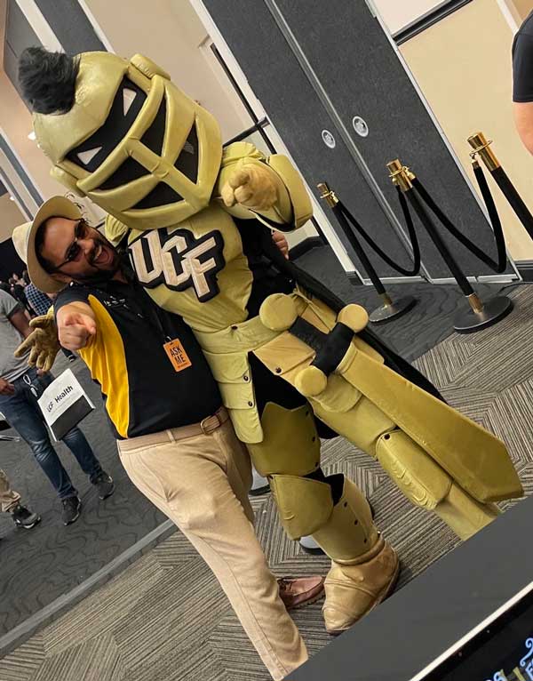Samuel Ensenat and Knightro pose playfully together and point toward the camera at UCF’s Annual Benefits Fair.