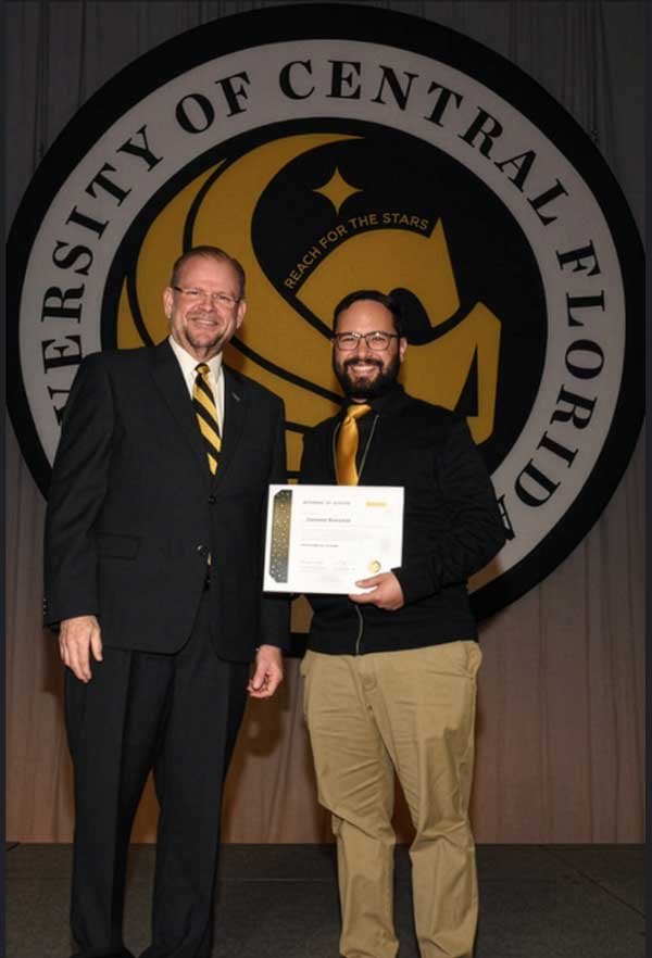 President Alexander N. Cartwright stands beside Samuel Ensenat, who holds his 20-year service award certificate at UCF’s Founders’ Day celebration.