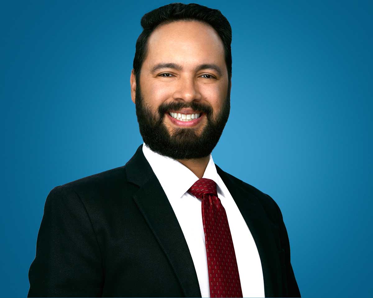Professional headshot of Samuel Ensenat smiling against a blue background.